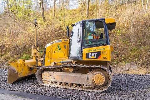 CAT chain tractor on gravel, autumn vegetation during construction work in the background, Hermann