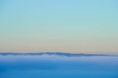Wind turbines on a hill with fog in the foreground and blue sky, Miltenberg, Spessart, Bavaria,