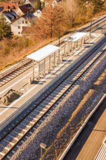 Station with platforms and tracks, surrounded by autumn leaves and houses, seen from a bird's eye