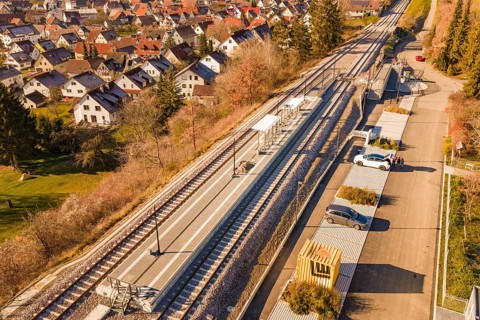 Aerial view of a village with a small train station surrounded by houses and autumn vegetation, new