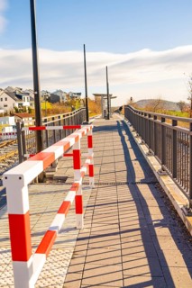 Footbridge with modern barrier and cast shadows in sunshine, new Hermann Hessebahn railway station,