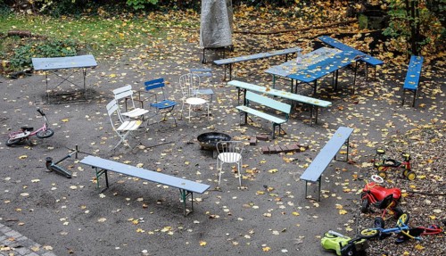 Chairs and tables stand unsorted around a fire bowl, a celebration in the garden is over, colorful