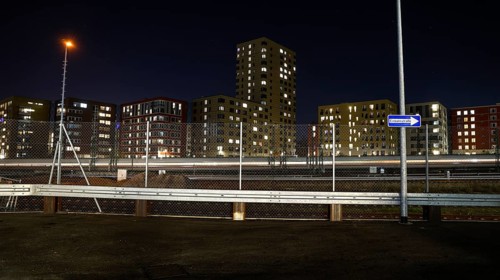 One way street on the fence, behind it a passing ICE train, illuminated apartments in a new housing