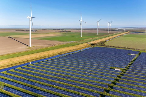 Aerial view over hybrid power plant combing solar photovoltaic modules and wind turbines, North