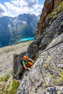 Mountaineer climbs on steep rock face in the secured via ferrata Crocodile Mountain Lake at