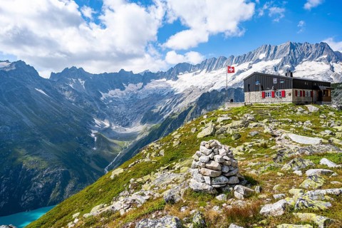 Mountain hut Bergseehütte with Swiss flag in picturesque mountain landscape, view of Damma Glacier