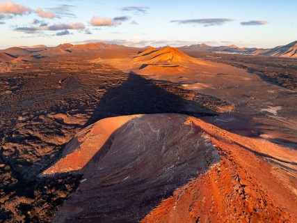 Picturesque volcanic landscape in evening light, red volcano Montaña Bermeja between lava fields,