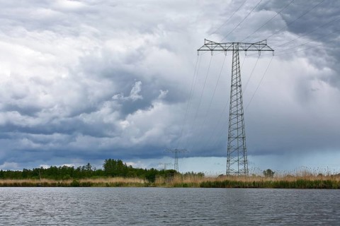 Landscape with high power pole under dramatic waterside cloud formations, Peenetal nature park