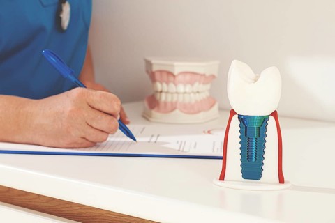 A dentist in a blue uniform studies patient information and prepares for treatment in a modern