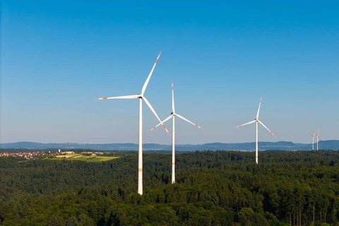 Wind power plants in a wooded area under a bright blue sky, near Schorndorf, Remstal,