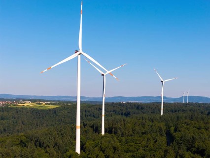 Wind turbines tower over a wooded landscape, dominated by clear skies, near Schorndorf, Remstal,