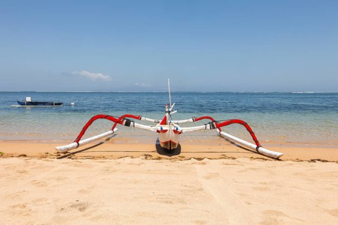 Colourfully painted outrigger fishing boats, (Junkung), on Sanur beach, Bali, Indonesia