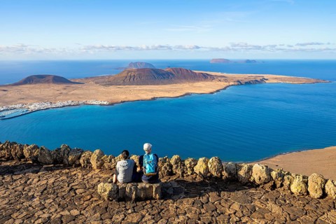 Tourists on a bench on the viewing platform at the Mirador del Río viewpoint, in the evening light,