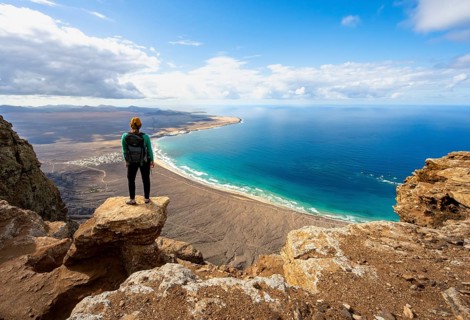 Young woman enjoying the view from the Risco de Famara cliffs to Famara beach, Playa de Famara with