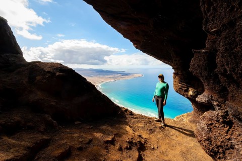 Tourist in the Cueva de las Cabras cave, young woman enjoying the view from the Risco de Famara