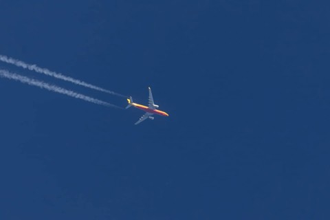 Boeing 767 jet cargo aircraft of DHL airlines flying in a blue sky with contrails or vapours trails