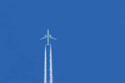 Boeing jet passenger aircraft flying in a blue sky with contrails or vapour trails behind, England,