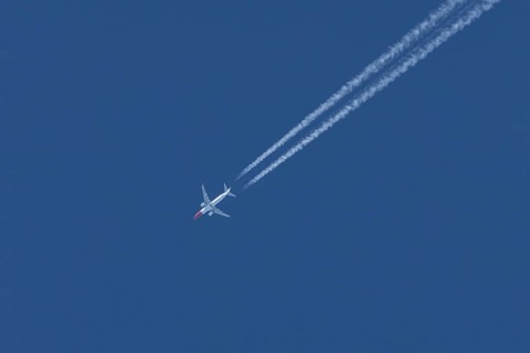 Boeing 737 jet passenger aircraft of Norwegian Air airlines flying in a blue sky with contrails or