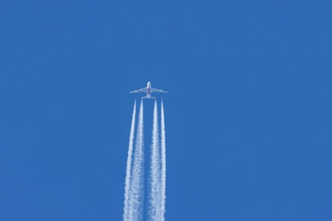 Airbus A380 jet passenger aircraft of Emirates airlines flying in a blue sky with contrails or