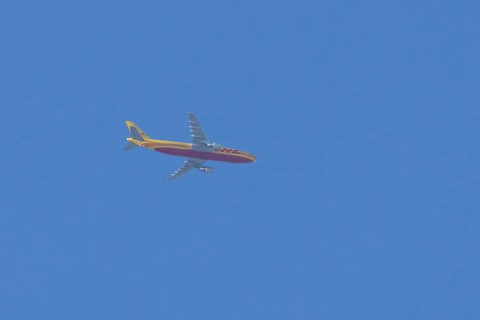 Boeing 767 jet cargo aircraft of DHL airlines flying in a blue sky, England, United Kingdom