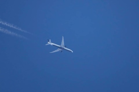 Boeing jet passenger aircraft flying in a blue sky with contrails or vapour trails behind, England,