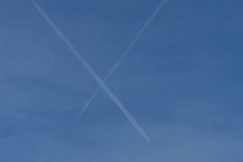 Aircraft contrails or vapour trails crossing in a blue sky, England, United Kingdom