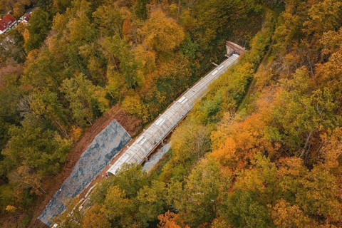 Aerial view of a railway tunnel under construction between autumnal forests, Hermann-Hesse-Bahn