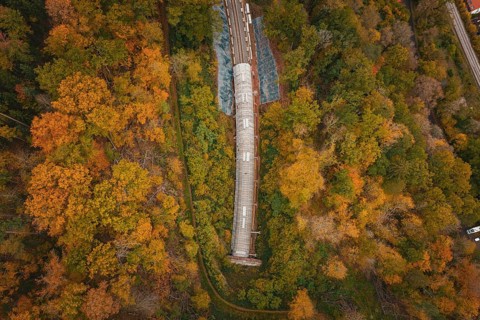 View from above of a tunnel under construction in a colorful forest, Hermann-Hesse-Bahn