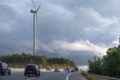 Tourist traffic on the A9 motorway during thunderstorms, a wind turbine in the back, Bavarian