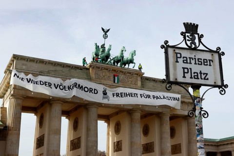 Several activists drop a banner with the inscription Never again genocide, freedom for Palestine