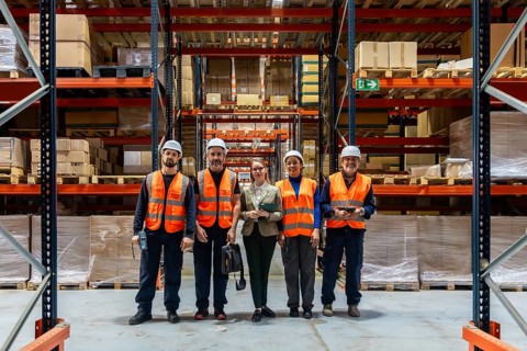 Diverse team of smiling warehouse workers and female manager standing in a modern logistics