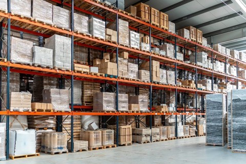 Industrial warehouse storing countless boxes, pallets, and goods wrapped in plastic on multiple