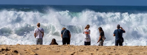 Tourists watch the waves of the Atlantic on the rocky plateau of Sito, also known as Forte São