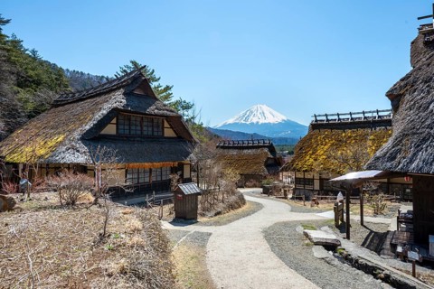 Iyashinosato open-air museum, old Japanese village with traditional houses, at the back volcano Mt.
