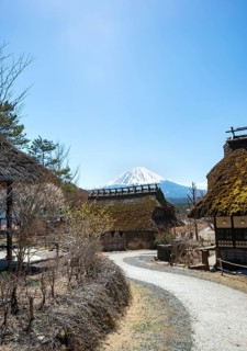 Iyashinosato open-air museum, old Japanese village with traditional houses, at the back volcano Mt.