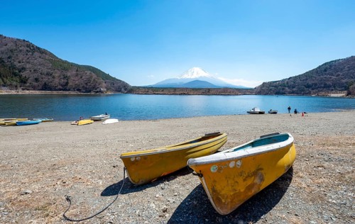 Rowing boats on shore, view across the lake to Mt Fuji volcano, Motosu Lake, Yamanashi Prefecture,