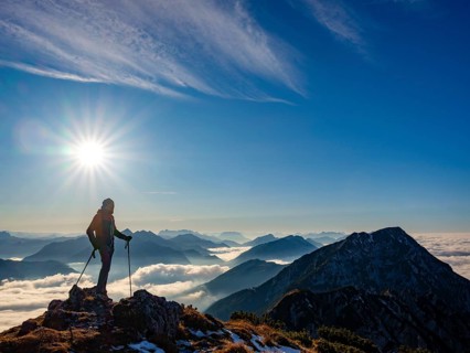 Mountaineer looking at blue-colored silhouette of mountains, fog in the valley, Hochstaufen,