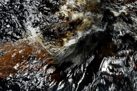 Stream flow with dark water, reflections and turbulences, long exposure, Sweden