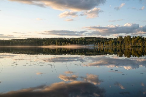 Clouds reflected on the water surface, forest lake, evening mood, at Sunne, Sweden