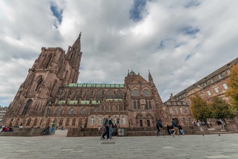 People walk in front of the majestic Strasbourg Cathedral, which is surrounded by historic