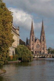 The two-towered church stands majestically on the banks of the river. Trees with golden leaves
