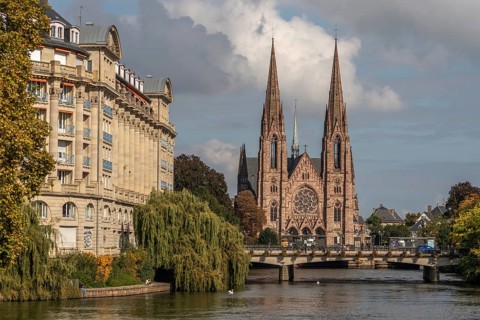 The two-towered church stands majestically on the banks of the river. Trees with golden leaves