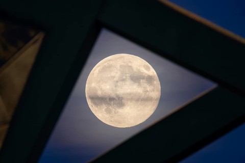 The full moon sweeps along the Frankfurt evening sky and passes the pillars of the rafter bridge,