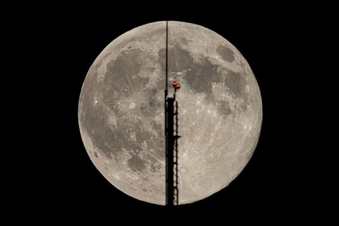 The full moon passes through the antenna on the roof of the European Central Bank (ECB), Frankfurt