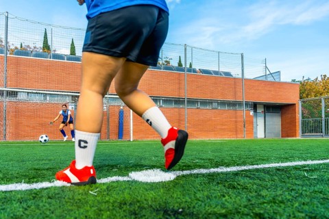 Football player preparing to shoot a penalty kick on an artificial turf field, with the opposing