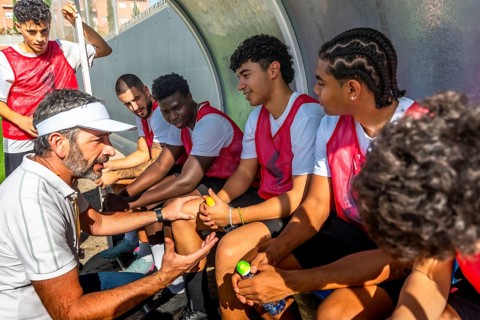 Soccer coach giving instructions and discussing tactics with his diverse young team of players