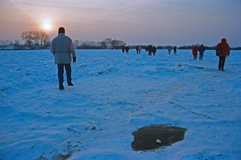 People walk across ice rink, sunset, frozen Elbe, Bleckede, Lower Saxony, Germany, February 9,
