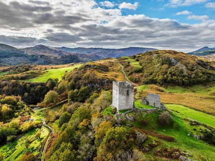 Autumn colours over Castell Dolwyddelan and Eryri Mountains from a drone, Snowdonia, Conwy County