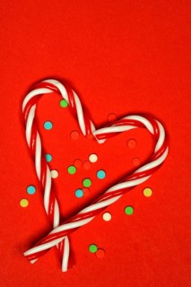 Candy canes and sugar confetti against red background, Christmas