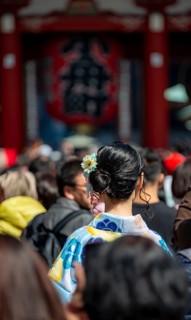Young Japanese woman wearing kimono surrounded by numerous visitors on Nakamise-dori shopping